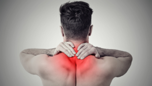 A man holds his hands to the back of his neck that is red with pain