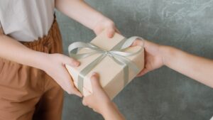 A person hands a neatly wrapped present to another person.